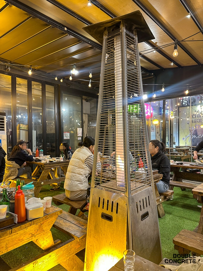 히터 주변에 앉아 따뜻하게 식사 중인 사람들