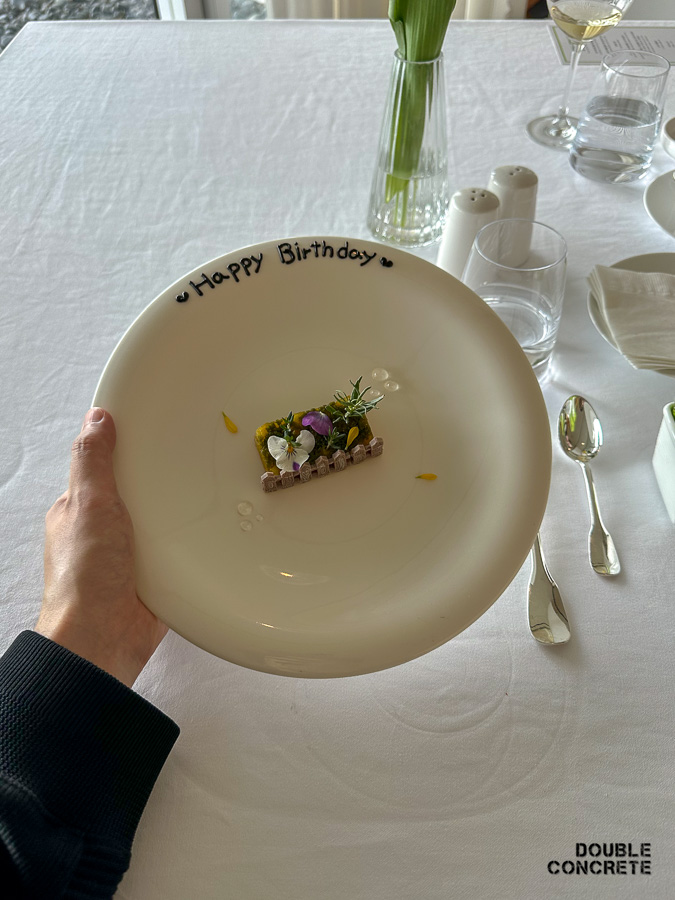 손으로 생일 축하 문구가 쓰인 디저트 접시를 들어 올린 모습