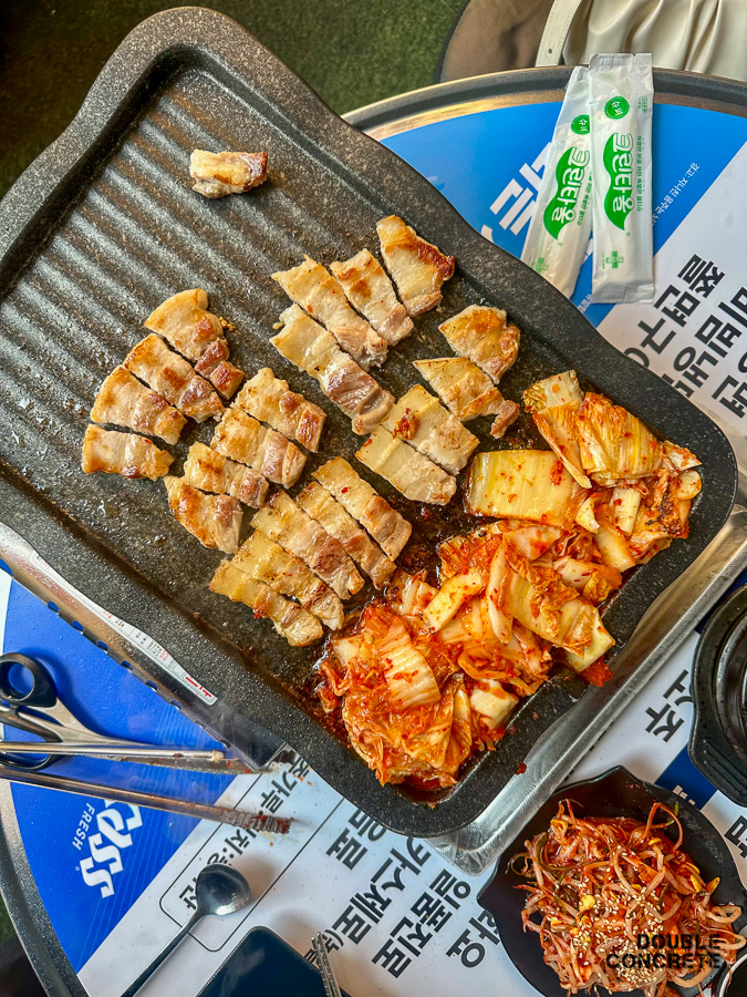 노릇노릇하게 구워진 삼겹살과 김치가 함께 놓인 불판