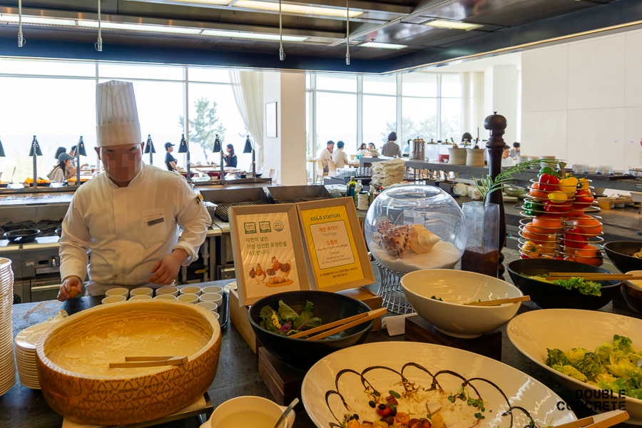 A chef preparing eggs at the egg station with a salad bar and buffet items at The Restaurant in Seamarq Hotel.