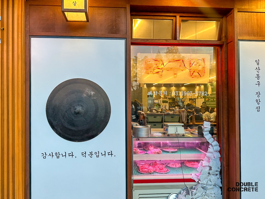 목구멍의 간판 옆에 위치한 ‘감사합니다, 덕분입니다.’라는 문구와 함께 보이는 고기 진열대.