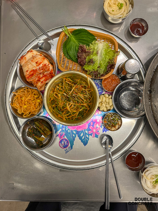 목구멍에서 제공되는 기본 반찬 세팅. 김치, 콩나물, 상추와 깻잎, 마늘 등이 포함됨.