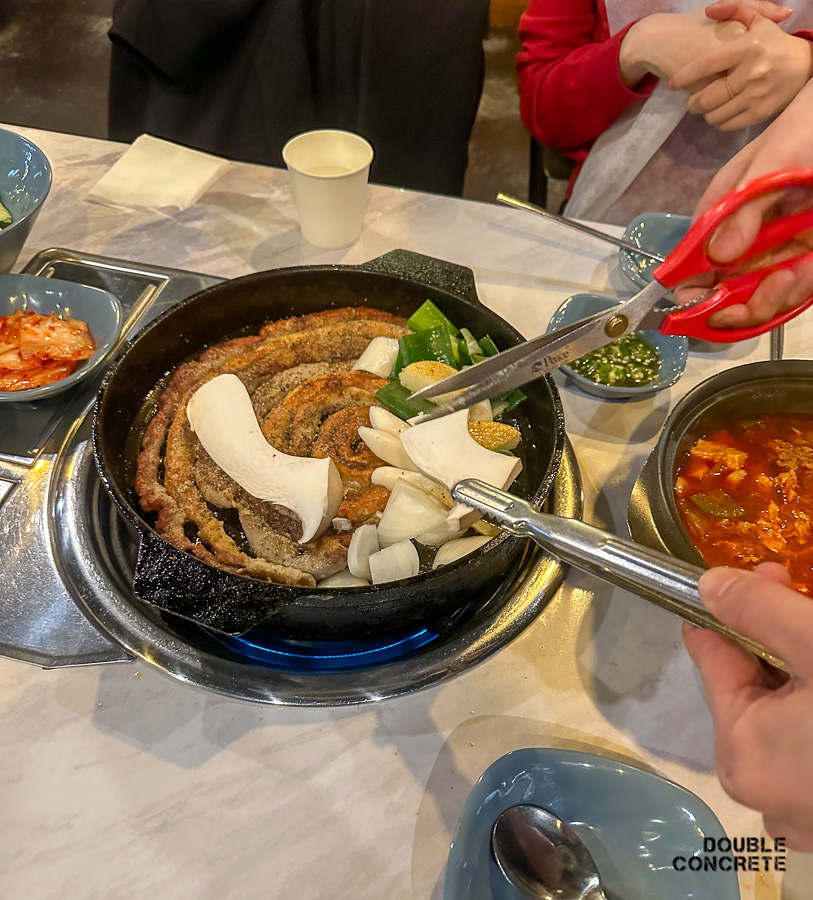 혜화곱창 직원이 곱창과 채소를 가위로 자르는 모습
