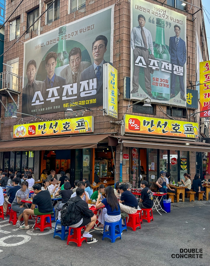원조 만선호프 앞 야외 좌석에서 많은 사람들이 삼삼오오 모여 술자리를 즐기고 있는 장면