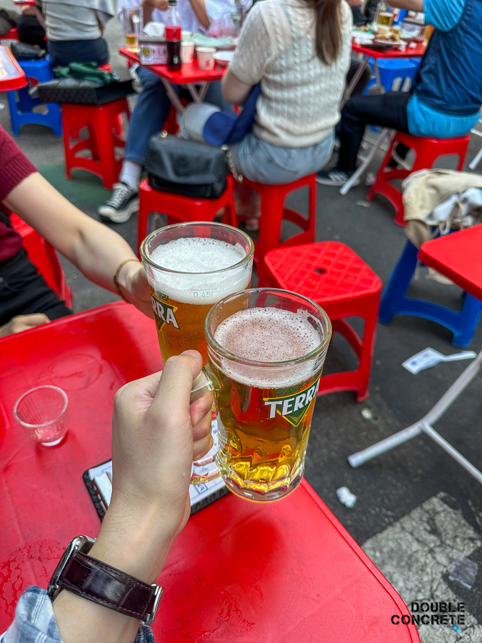 테라 맥주잔으로 건배하는 두 사람의 손과 빨간 테이블 위 분위기