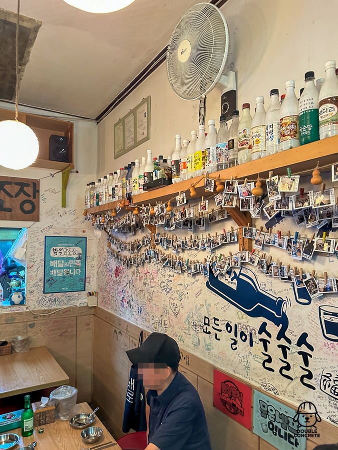 막걸리 병과 폴라로이드 사진으로 가득한 백석양조장 벽