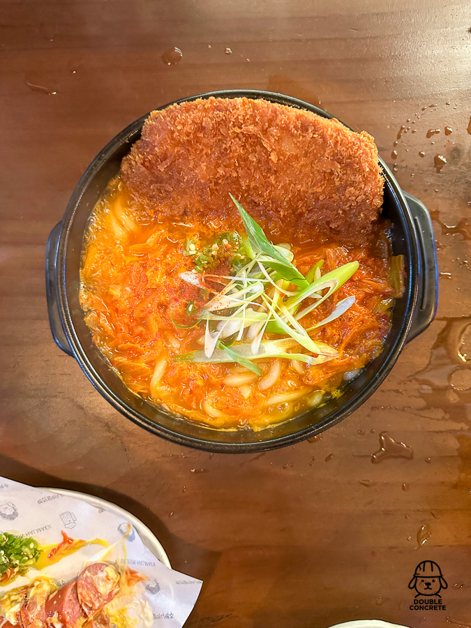 김치우동 위에 얹어진 바삭한 돈까스와 송송 썬 파가 올라간 뜨거운 안주