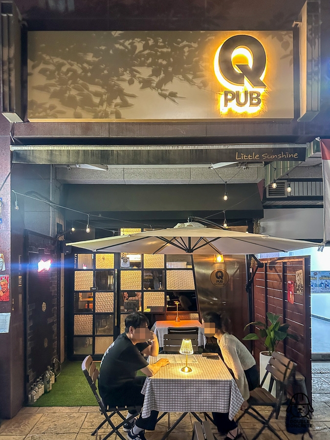Q PUB 외관과 야외 테이블에 앉아 있는 손님들의 모습